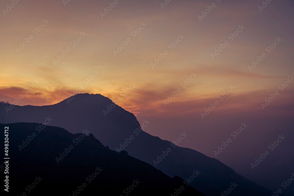 a beautiful morning picture of the sun,rising over the mountains, at the top station munnar image taken from munnar, kerala,