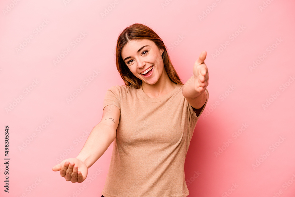 Young caucasian woman isolated on pink background feels confident giving a hug to the camera. Young caucasian woman isolated on pink background feels confident giving a hug to the camera.