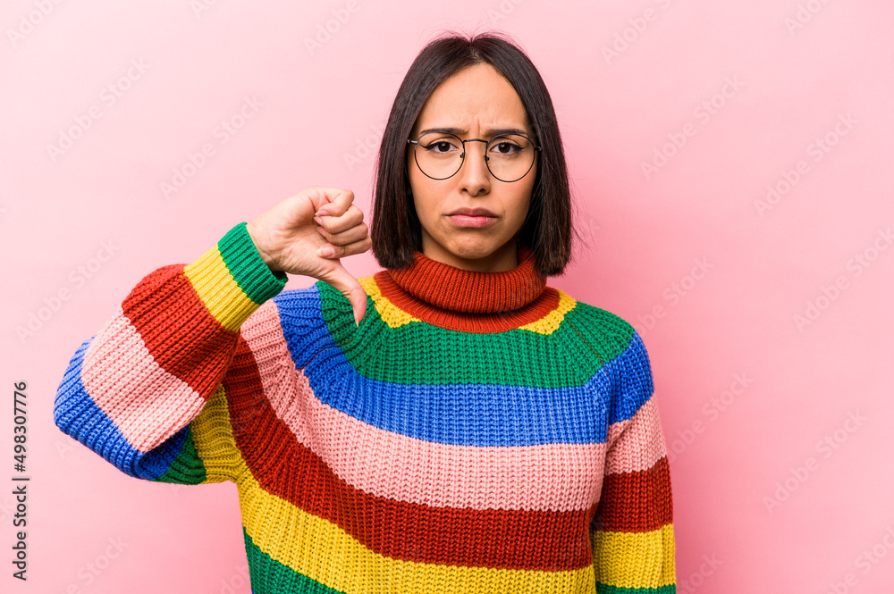 Young hispanic woman isolated on pink background showing a dislike gesture, thumbs down. Disagreement concept. Young hispanic woman isolated on pink background showing a dislike gesture, thumbs down. Disagreement concept.