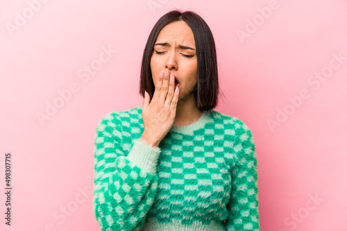 Young hispanic woman isolated on pink background yawning showing a tired gesture covering mouth with hand.