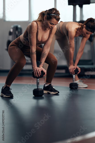 Fototapeta Naklejka Na Ścianę i Meble -  Pretty women working out in a gym. Adult ladies with beautiful shaped bodies.