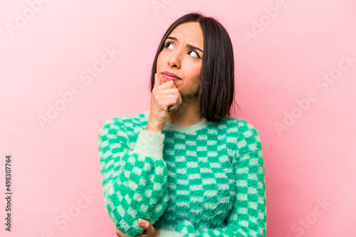 Young hispanic woman isolated on pink background thinking and looking up, being reflective, contemplating, having a fantasy Fototapet