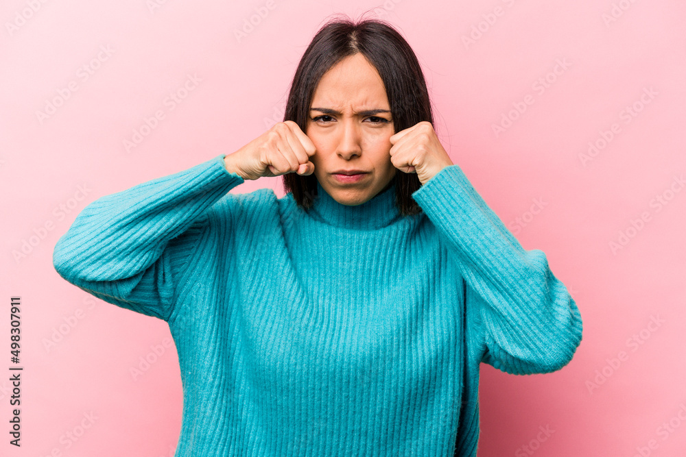 Young hispanic woman isolated on pink background throwing a punch, anger, fighting due to an argument, boxing. Young hispanic woman isolated on pink background throwing a punch, anger, fighting due to an argument, boxing.