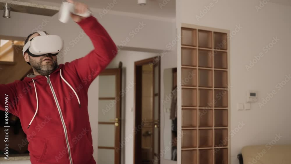 Man on Virtual Reality Glasses Doing Variation of Online Fitness Training. Man Wearing Virtual Reality Headset Holding Gaming Controllers. Sportsman in VR Headset Working Out at Home. Metaverse Oculus
