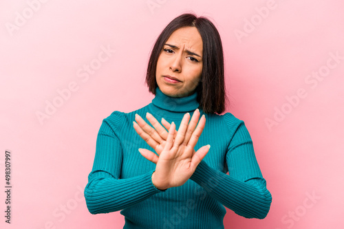 Foto Young hispanic woman isolated on pink background doing a denial gesture