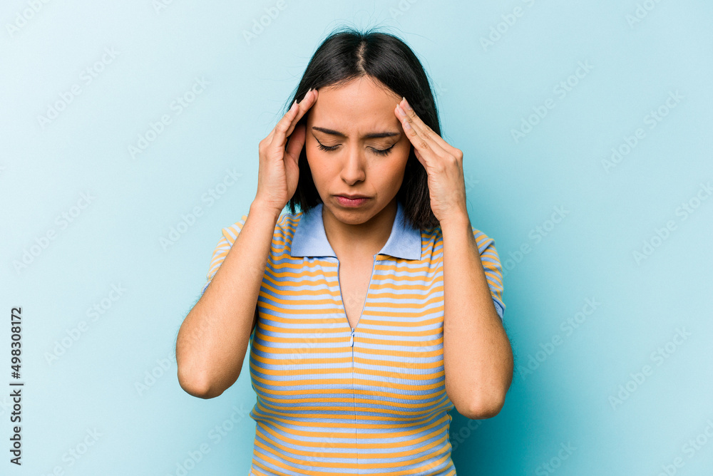Young hispanic woman isolated on blue background touching temples and having headache. Young hispanic woman isolated on blue background touching temples and having headache.