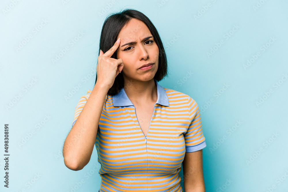 Young hispanic woman isolated on blue background pointing temple with finger, thinking, focused on a task. Young hispanic woman isolated on blue background pointing temple with finger, thinking, focused on a task.
