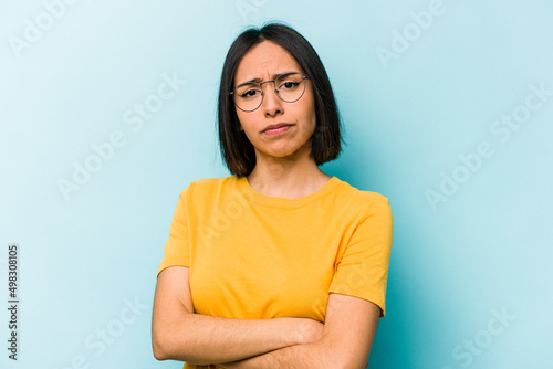 Young hispanic woman isolated on blue background suspicious, uncertain, examining you.
