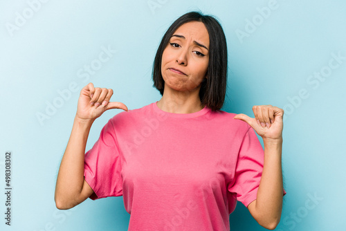 Young hispanic woman isolated on blue background feels proud and self confident, example to follow.