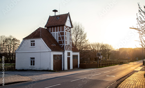 Fototapeta Naklejka Na Ścianę i Meble -  Beautiful old German house by the road at sunset.