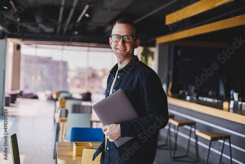 Wallpaper Mural Male entrepreneur in black shirt and glasses standing in office with laptop in hand, successful corporate boss feeling good from rich lifestyle Torontodigital.ca