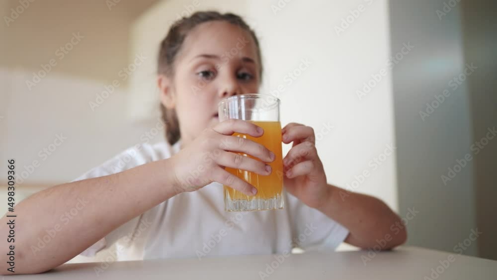 girl child drinking juice. happy family a healthy eating kid dream concept. daughter girl drinking yellow juice from a glass cup in the kitchen. child drinking indoors fruit juice girl child drinking juice. happy family a healthy eating kid dream concept. daughter girl drinking yellow juice from a glass cup in the kitchen. child drinking indoors fruit juice