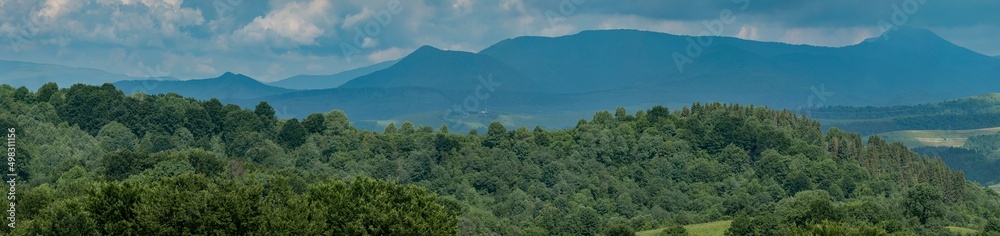 Panoramic green forest on blue mountains and sky background. View of the Carpathian mountains in spring, Ukraine. Mountain tourism. Tourism and travel concept. Panoramic green forest on blue mountains and sky background. View of the Carpathian mountains in spring, Ukraine. Mountain tourism. Tourism and travel concept.