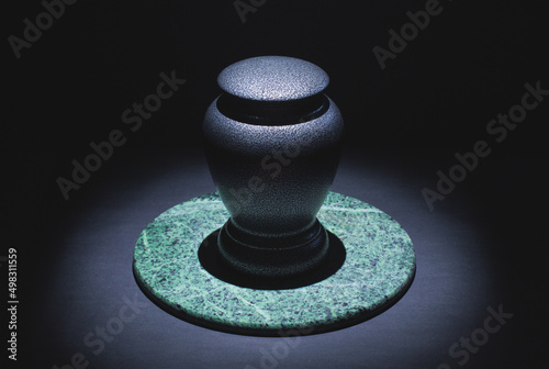 Cremation urn on marble and black. Low key image.