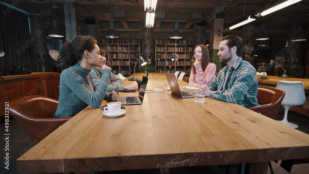 Group of diverse young colleagues discuss plans at conference table Group of diverse young colleagues discuss plans at conference table
