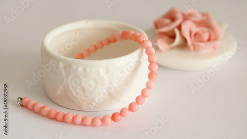 Pink coral bracelet and porcelain jewelry box isolated on white background, on table. 