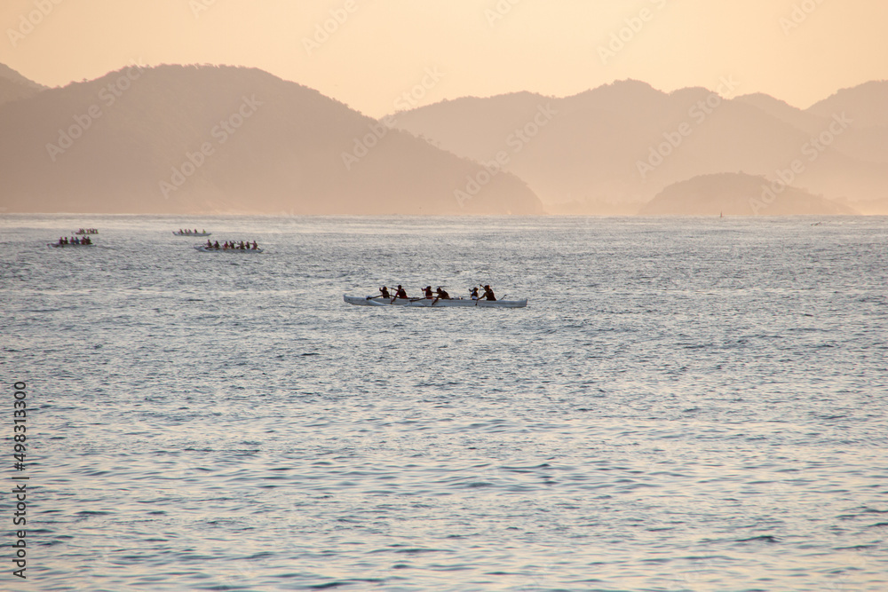 silhouette of people paddling a hawaiian canoe at Copacabana Beach in Rio de Janeiro. silhouette of people paddling a hawaiian canoe at Copacabana Beach in Rio de Janeiro.