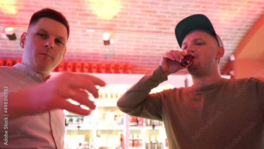 Two young men drink strong alcohol. Tasting set of alcoholic beverages. Degustation on the bar. Face grimace. Cheers drink