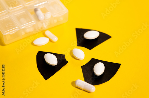 Multiple anti-radiation pills based on iodine on a yellow background and the radiation warning sign