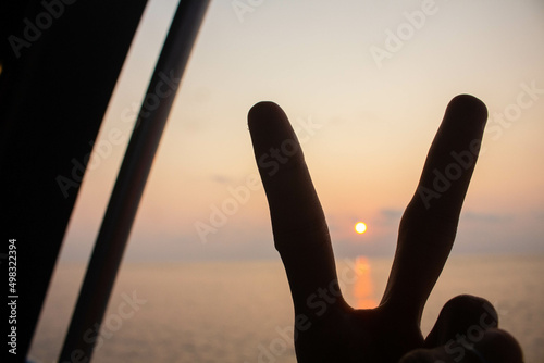 Silhouette peace sign in the sea at the sunset time