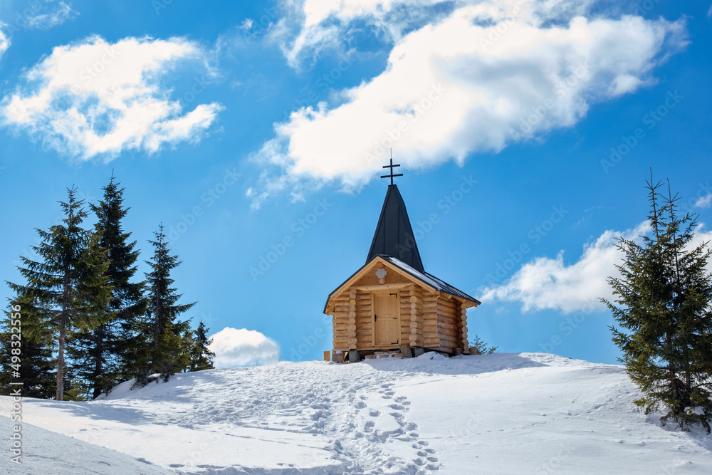 A group of hikers standing near a Romanian wooden chalet on the top of a snowy hill