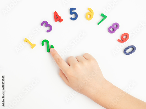 The child uses the index finger to move the number two up. Early education. We learn colors and count from zero to ten