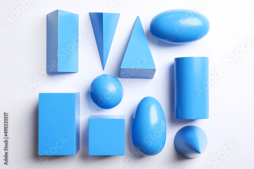 Set of blue wooden geometrical objects on white background, top view. Montessori toy