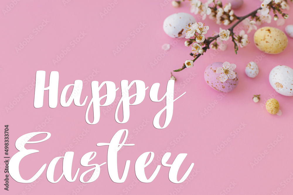 Happy Easter greeting card. Happy Easter text and colorful Easter chocolate eggs and cherry blossoms border on pink background. Seasons greeting card, handwritten lettering
