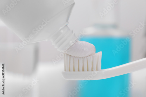 Fototapeta Naklejka Na Ścianę i Meble -  Squeezing paste onto toothbrush against blurred background, closeup