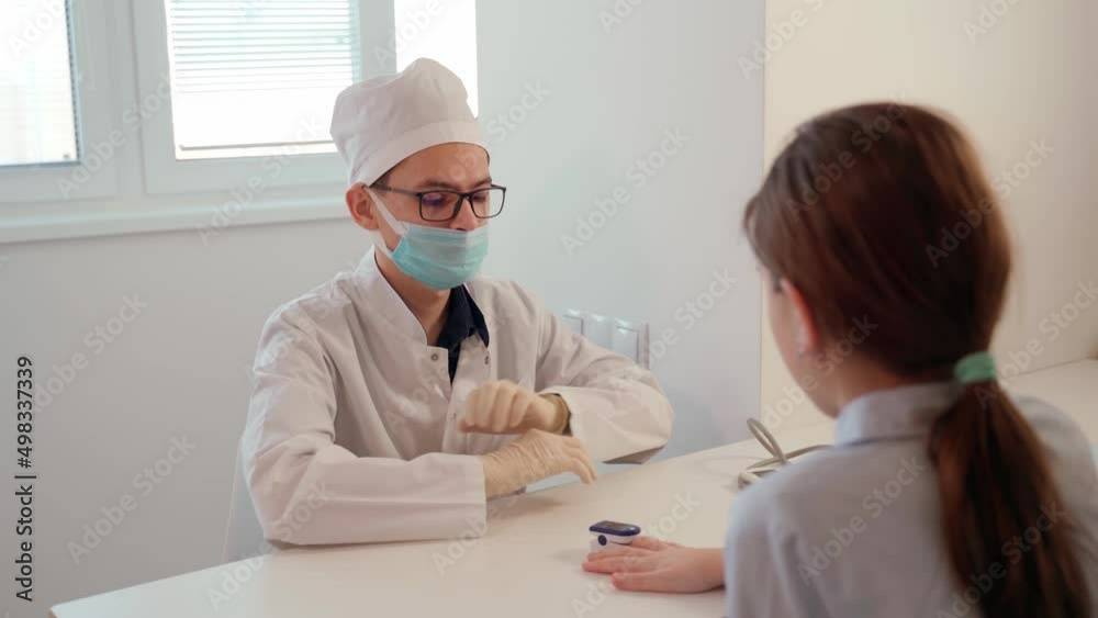 A young Doctor with a pulse oximeter measures the level of oxygen in the blood of a patient in a medical office. Prevention, treatment and health control. A young Doctor with a pulse oximeter measures the level of oxygen in the blood of a patient in a medical office. Prevention, treatment and health control.