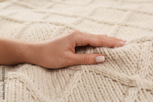Woman touching soft beige knitted fabric, closeup