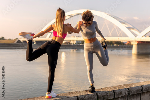 Two woman exercise and stretching outside near the river