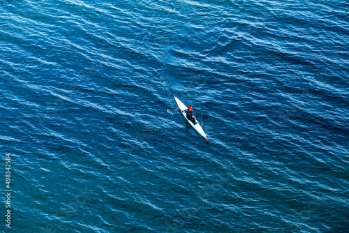  the surface of the sea and on it a tiny canoe with a rower fighting the waves, top view