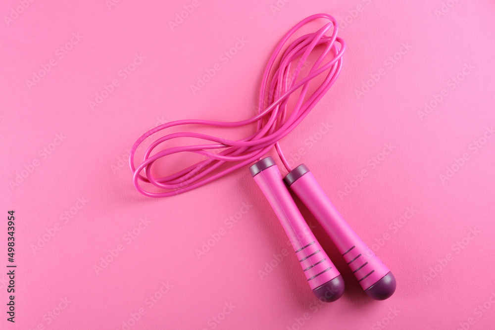 Skipping  rope on pink background, top view. Sports equipment