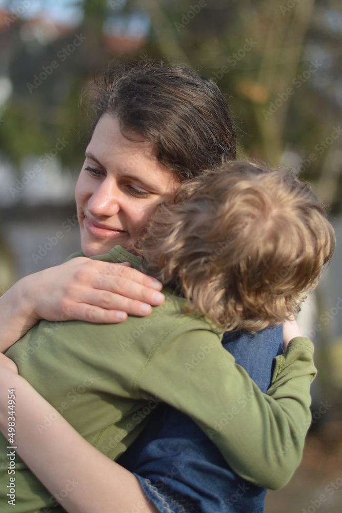 Mother holding child in her arms with love in a garden outdoors Mother holding child in her arms with love in a garden outdoors