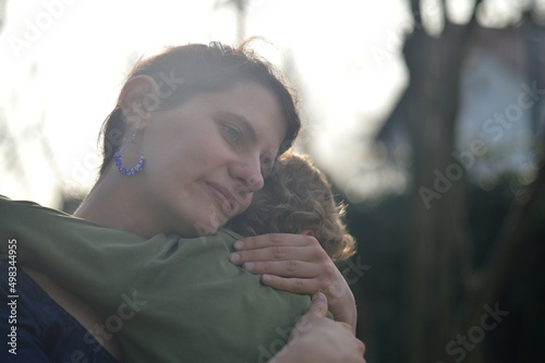 Fotografie Mother holding child in her arms with love in a garden outdoors