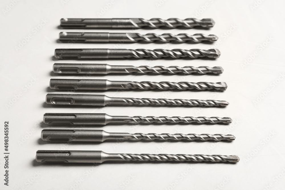 Many different drill bits on white table Many different drill bits on white table