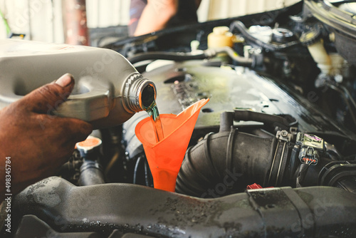 Car maintenance. Car service. Car technician pouring the fresh transmission oil at the car service station.