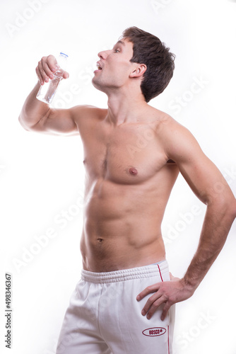 body of a young caucasian male athletic naked to the waist isolated on white background with a bottle of water in hand
