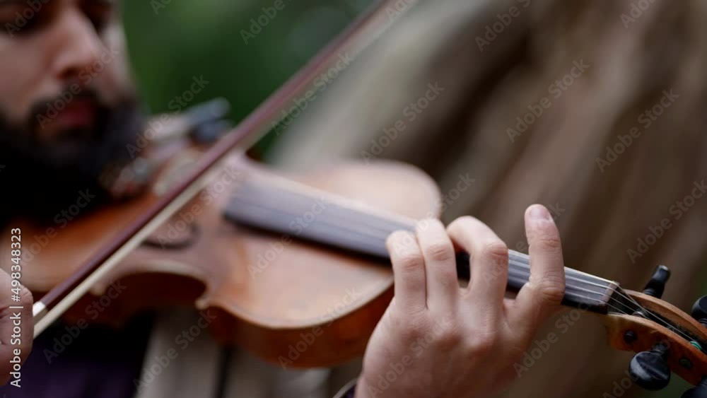 old fiddle in hands of musician, closeup view, violinist is playing music in forest old fiddle in hands of musician, closeup view, violinist is playing music in forest