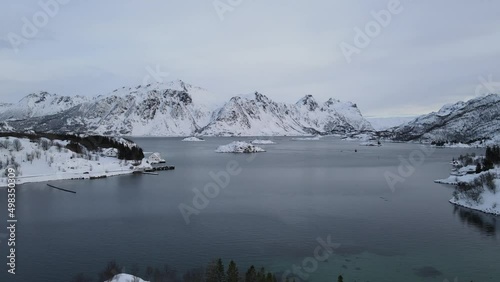The flight above sea and small islands surrounded by mountains in winter