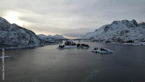 The flight above sea and small islands surrounded by mountains towards bridge  in winter