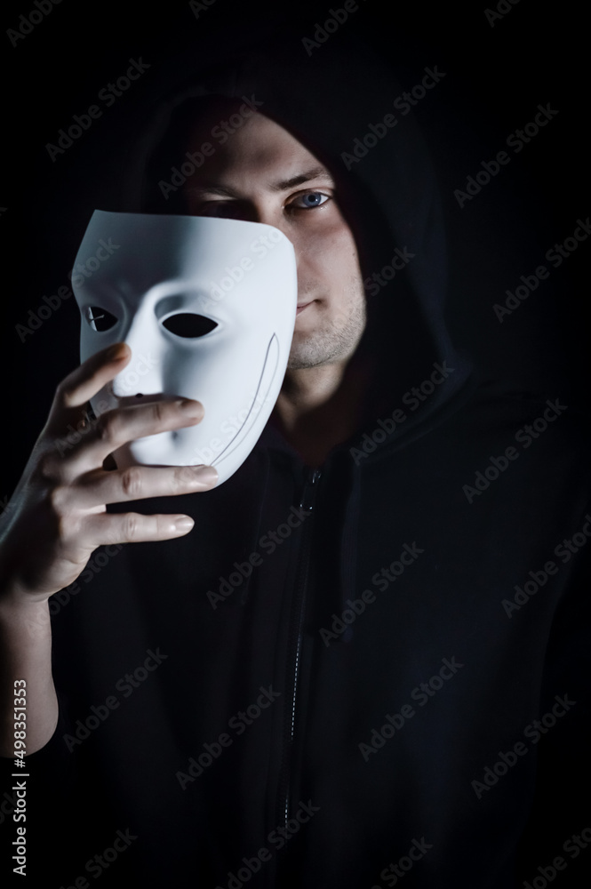 Portrait of a young hooded man taking off his mask, concept for being true and authentic Portrait of a young hooded man taking off his mask, concept for being true and authentic