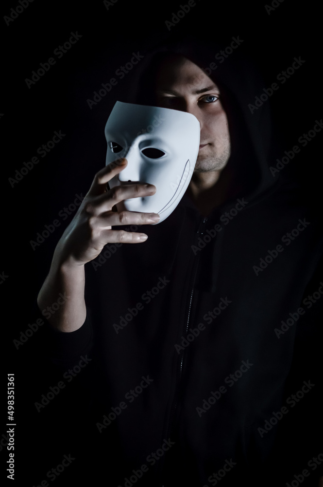 Portrait of a young hooded man taking off his mask, concept for being true and authentic Portrait of a young hooded man taking off his mask, concept for being true and authentic