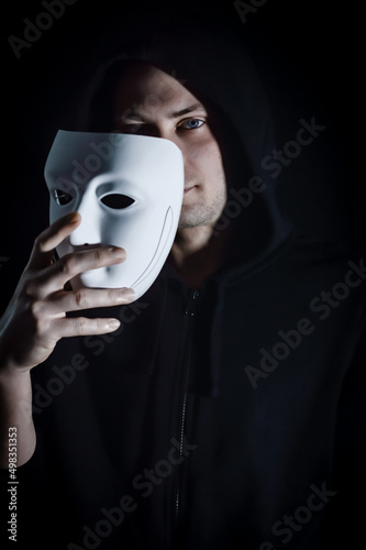 Portrait of a young hooded man taking off his mask, concept for being true and authentic