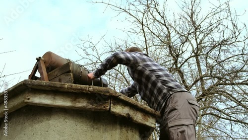 Man in a checkered shirt fetching water from a well. Fresh cold water splashing from a bucket
