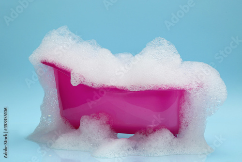 Photography Toy bathtub overflowing with foam on light blue background