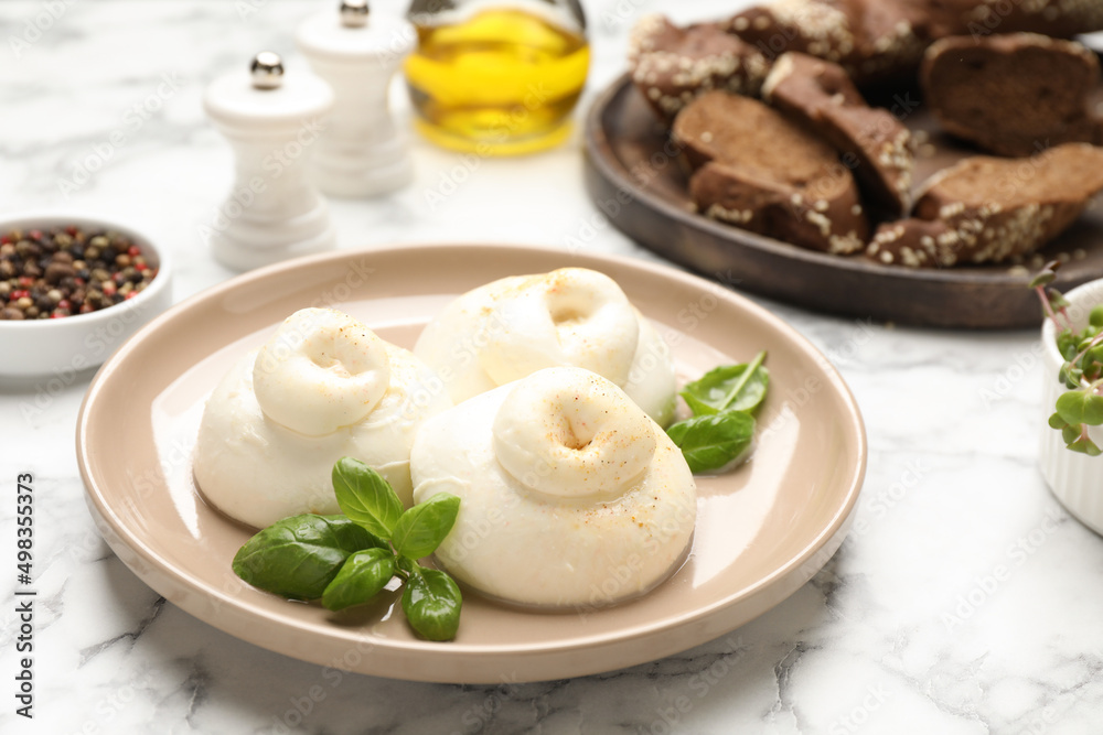 Delicious burrata cheese with basil on white marble table Delicious burrata cheese with basil on white marble table