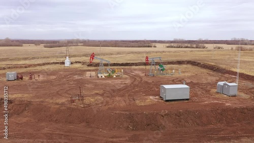 Pump jack in vast oil fields in Russia. Pipelines transporting oil from oil pumps, aerial drone shot