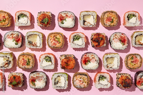 Various sushi rolls on pink background, top view.